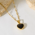 Gros plan détaillé du pendentif cœur doré avec onyx noir sur une texture blanche - Style Coeur Doré (290)
