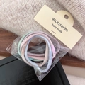 Macro view of pastel-colored elastic hair ties in a pack with a handmade tag label - Wide Striped Style