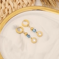 Orecchini a occhio dorati con perline blu e zirconi su vassoio in marmo bianco - Design Zirconia d'Oro