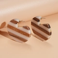 Detailed close-up of C-shaped earrings made of natural wood and ivory resin stripes - White