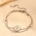 Macro-opname van de dubbellaagse stalen armband met ster-reliëf hanger en zilveren kralen - Dubbellaagse Slangenketting met Ster Ronde Tag (I113) / Stalen Ster Armband
