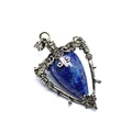 Macro view of blue stone pendant with ornate silver metal wings and star patterns - Lapis Lazuli