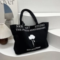 Black and white canvas tote bag with floral print and NKK ART STUDIO typography design - Black