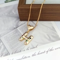 Detailed macro view of gold letter H pendant with colorful stones on vintage book page - Letter H