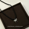 Minimalist black beaded necklace featuring a silver bow-knot pendant on a display pad - Black Glass Bead Bowknot Pendant Necklace