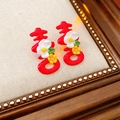 Detail van rode Xi-karakter oorbellen met bloemmotieven en groene bladeren in houten lijst - Rood (Zilveren oorsteker)