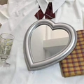 Detailed close-up of a heart-shaped makeup mirror with silver beaded edge on fabric - Silver