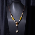 Detailed view of ethnic ceramic beads on a brown braided rope necklace with tassel - X470-1 Flower Small Ball