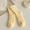 Yellow coral fleece socks with white bow accents on a cozy indoor tabletop - One Size / Yellow