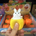 Squishy carrot cup toy with a pop-up white rabbit being squeezed by a hand - Yellow Cup With White Rabbit