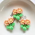 Detail shot of cute resin orange flower charms with green leaves on a white tray - Double Sunflower