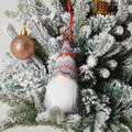 Gros plan d'un gnome de Noël tricoté suspendu à une branche de sapin enneigée et décorée - C2-1 Petit Ornement Gris Style Z (Bonnet Tricoté Rayé Gris et Rouge)
