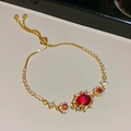 Detalle de la pulsera floral bañada en oro con gemas rojas y cierre ajustable - Pulsera / Dorado-Rojo