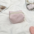 Detail of pink makeup bag featuring embossed heart patterns and durable cream zipper - Pink