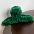 Detailed view of dark green plush faux fur hair claw clip on a wooden surface - Green