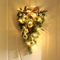 Goldener Weihnachts-Türhänger mit LED-Lichtern und Schleife an einer beigen Haustür - Goldener handbemalter Kugel-Invertierter Baum - Mit Lichtern