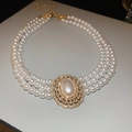 Primer plano de collar de perlas de tres capas con colgante ovalado de diamantes - Collar de perlas de triple capa / Dorado