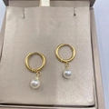 Elegant gold hoop earrings with white pearl pendants displayed on a beige silk cushion - Pearl Gold