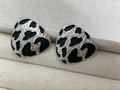 Macro shot of silver-tone irregular earrings with black animal print on fabric background - Triangle - White Gold