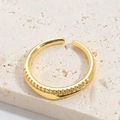 Detailed close-up of a gold textured open ring on a natural stone background - White Zirconia (Small)