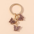 Llavero de mariposa con lentejuelas moradas y aro dorado para bolsos y mochilas - Brillo Púrpura (YZ172zongse)