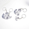 Detailed view of three acrylic raccoon keychains with watercolor art and silver rings - Acrylic Raccoon