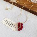 Vista dettagliata della collana d'oro con pendenti a uva floccati rosso scuro su lino - Stile con Perline di Bacche / Collana con Pendente Rosso