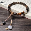 Close-up of wooden bead bracelet with white Bodhi seed pendant on a calligraphy book - Straight Cut 7x8mm Wood Beads With White Pumpkin Accessory