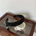 Detail van een handgemaakte zwart geruite haarband op een houten sieradendoos met accessoires - Zwart