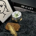 Aromatic dried flower candle in a white and green floral tin container on a plush rug - H12 Tuberose