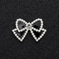 Detail of a black enamel bow charm with pearl border and a large central crystal - Silver Base Black Bow