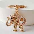 Close-up of golden elephant keychain with white enamel and sparkling rhinestones - Brown