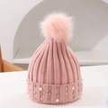 Close-up of pink knit hat featuring faux fur pom-pom and white pearl embellishments - One Size / Pink