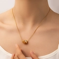 Detail of a golden bean pendant necklace with a round white gemstone on a model - Bean Style (TYN0201)