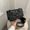 Schwarze Stepptasche mit Goldkette und gemustertem breitem Gurt auf Marmorsockel - Schwarz