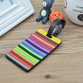 Rainbow striped soft PVC luggage tag with black strap on a wooden desk - Stripe