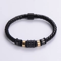 Dettaglio del bracciale in pelle intrecciata nera con anelli in oro e chiusura magnetica - Nero e Oro