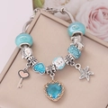 Detail view of a sky blue charm bracelet with heart crystals and starfish pendant - Blue