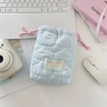 Close-up of a blue quilted drawstring camera bag on a desk with macaron color tones - Quilted Cloud Light Blue