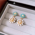 Detalle de pendientes de margarita con esmalte azul y blanco y centros de cristal - Dorado