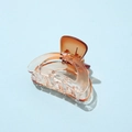 Macro shot of an amber acetate hair claw clip with transparent finish on light blue background - Half Round Orange