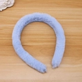 Detail view of a soft light blue faux fur headband on a minimalist wood surface - Sea Blue (Faux Rabbit Fur)