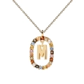 Detail of gold letter M pendant surrounded by colorful cubic zirconia on a gold chain - M