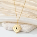 Macro shot of gold Evil Eye necklace with black stone on white silk and mineral stones - Round Black Zirconia Eye