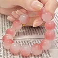 Pink gradient blush beaded bracelet held against a literary book background - S070-12mm Bracelet [icy Pink] Glass Material #sz559