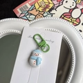 Detail shot of a cute snowman keychain with blue scarf and green clip on a display card - Snowman