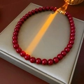 Détail du collier à perles rouges en acier inoxydable avec fermoir doré sur boîte - Diamètre 9mm