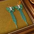 Detailed view of vintage zircon butterfly tassel earrings on green velvet background - Earring Hooks / Green
