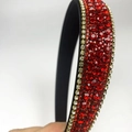 Macro detail of the densely set red rhinestones on the wide black cushioned headband - Red