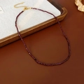 Détail d'un collier de perles rouge foncé avec fermoir doré et chaîne de réglage - Rouge